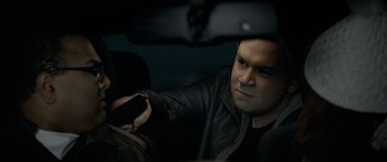 Movie still from “Broken” (2021), directed by Patrick Phillips – A man in a leather jacket holding a cell phone; Close Up shot, High angle