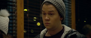 Movie still from “Broken” (2021), directed by Patrick Phillips – A young man wearing a gray hat and a black jacket; Close Up shot, Over the shoulder angle