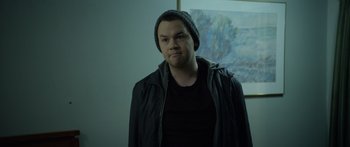 Movie still from “Broken” (2021), directed by Patrick Phillips – A man in a black jacket wearing a black hat; Close Up shot, Over the shoulder angle