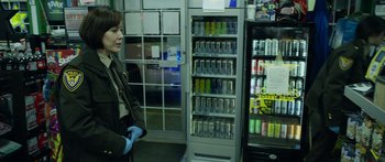 Movie still from “Broken” (2021), directed by Patrick Phillips – A woman standing in front of a vending machine; Medium shot, Over the shoulder angle