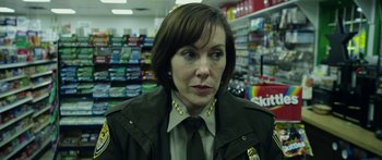 Movie still from “Broken” (2021), directed by Patrick Phillips – A woman in a police uniform in front of a store; Close Up shot, Over the shoulder angle