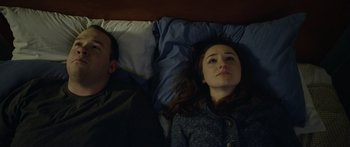 Movie still from “Broken” (2021), directed by Patrick Phillips – A man and a woman laying in a bed together; Close Up shot, Overhead angle