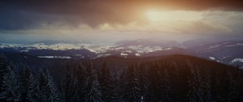 Movie still from “Broken” (2021), directed by Patrick Phillips – The sun is setting over a snowy mountain; Extreme Wide shot, High angle