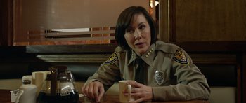 Movie still from “Broken” (2021), directed by Patrick Phillips – A police officer sitting at a table with a cup of coffee; Close Up shot, Over the shoulder angle