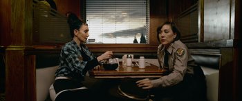 Movie still from “Broken” (2021), directed by Patrick Phillips – Two women sitting at a table in front of a window; Medium shot, Over the shoulder angle