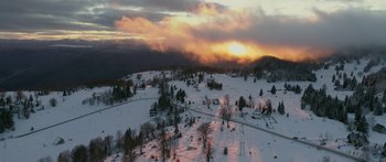 Movie still from “Broken” (2021), directed by Patrick Phillips – An aerial view of a snow covered field with a sunset in the background; Extreme Wide shot, High angle