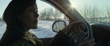 Movie still from “Broken” (2021), directed by Patrick Phillips – A woman driving a car in the snow with the sun in the background; Close Up shot, Over the shoulder angle