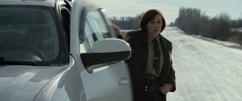 Movie still from “Broken” (2021), directed by Patrick Phillips – A female police officer standing in front of a white car; Medium shot, Over the shoulder angle