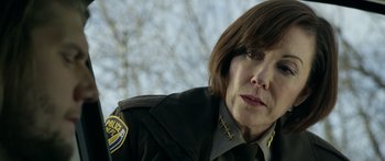 Movie still from “Broken” (2021), directed by Patrick Phillips – A woman in a police uniform looking at the camera; Close Up shot, Over the shoulder angle