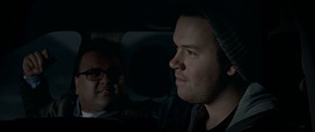 Movie still from “Broken” (2021), directed by Patrick Phillips – A man in a car with another man in the back seat; Close Up shot, Over the shoulder angle
