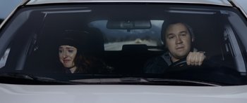 Movie still from “Broken” (2021), directed by Patrick Phillips – A man and a woman sitting in the back seat of a car; Medium shot, Low angle