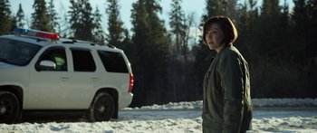 Movie still from “Broken” (2021), directed by Patrick Phillips – A woman standing next to a white suv in the snow; Medium shot, Over the shoulder angle
