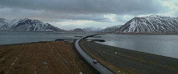 Movie still from “Broken” (2021), directed by Patrick Phillips – An aerial view of a road near a body of water; Extreme Wide shot, High angle