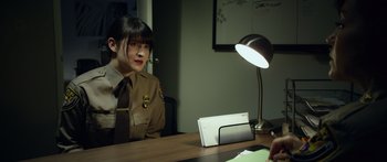Movie still from “Broken” (2021), directed by Patrick Phillips – A woman sitting at a table with a laptop; Medium shot, Over the shoulder angle