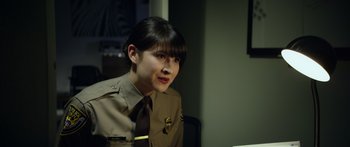 Movie still from “Broken” (2021), directed by Patrick Phillips – A woman in a uniform is sitting at a table; Close Up shot, Over the shoulder angle