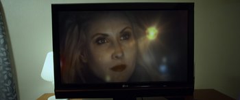Movie still from “Broken” (2021), directed by Patrick Phillips – A television screen showing a woman's face with light coming out of it; Extreme Close Up shot, Over the shoulder angle