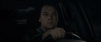 Movie still from “Broken” (2021), directed by Patrick Phillips – A man sitting in the driver's seat of a car at night; Close Up shot, High angle