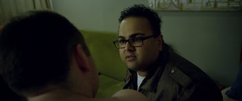 Movie still from “Broken” (2021), directed by Patrick Phillips – A man wearing glasses is sitting on a couch; Close Up shot, Over the shoulder angle