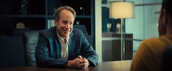 Movie still from “Bros” (2022), directed by Nicholas Stoller – A man sitting at a table with his arms crossed; Close Up shot, Over the shoulder angle