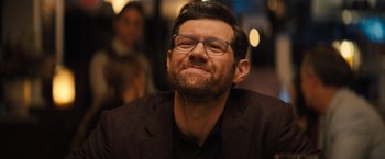 Movie still from “Bros” (2022), directed by Nicholas Stoller – A person wearing glasses and a jacket; Close Up shot, Over the shoulder angle