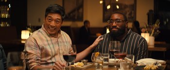 Movie still from “Bros” (2022), directed by Nicholas Stoller – Two men sitting at a table with wine glasses; Medium shot, Over the shoulder angle