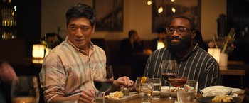 Movie still from “Bros” (2022), directed by Nicholas Stoller – A couple of men sitting at a table with wine glasses; Medium shot, Over the shoulder angle