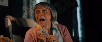 Movie still from “Bros” (2022), directed by Nicholas Stoller – An older woman holding a phone up to her mouth; Close Up shot, High angle