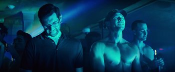 Movie still from “Bros” (2022), directed by Nicholas Stoller – Two men are standing in a dark room; Medium shot, Low angle
