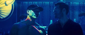 Movie still from “Bros” (2022), directed by Nicholas Stoller – A man in a hat and a man in a black shirt; Medium shot, Over the shoulder angle