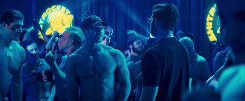 Movie still from “Bros” (2022), directed by Nicholas Stoller – A group of men standing in a blue room; Medium shot, Over the shoulder angle
