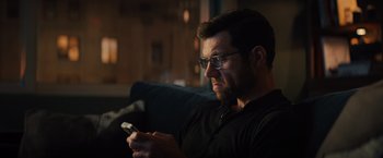 Movie still from “Bros” (2022), directed by Nicholas Stoller – A person sitting on a couch looking at a phone; Close Up shot, Low angle