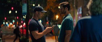Movie still from “Bros” (2022), directed by Nicholas Stoller – Two men standing next to each other looking at a cell phone; Medium shot, Over the shoulder angle