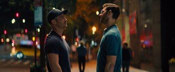 Movie still from “Bros” (2022), directed by Nicholas Stoller – A couple of men standing next to each other on a sidewalk; Medium shot, Over the shoulder angle
