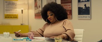 Movie still from “Bros” (2022), directed by Nicholas Stoller – A woman sitting at a table with papers in front of her; Close Up shot, Over the shoulder angle