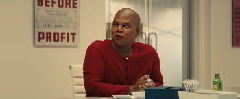 Movie still from “Bros” (2022), directed by Nicholas Stoller – A man sitting at a table in front of a white wall; Medium shot, Over the shoulder angle