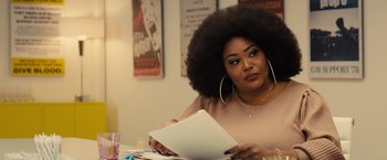 Movie still from “Bros” (2022), directed by Nicholas Stoller – A woman sitting at a table looking at a piece of paper; Close Up shot, Over the shoulder angle