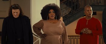 Movie still from “Bros” (2022), directed by Nicholas Stoller – A woman in a brown dress with her hands on her hips; Medium shot, Over the shoulder angle