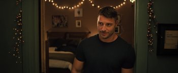 Movie still from “Bros” (2022), directed by Nicholas Stoller – A person wearing a black shirt in a room; Medium shot, Over the shoulder angle