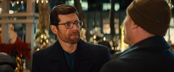Movie still from “Bros” (2022), directed by Nicholas Stoller – A person wearing glasses and a jacket; Close Up shot, Over the shoulder angle