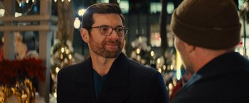 Movie still from “Bros” (2022), directed by Nicholas Stoller – A person wearing glasses and a jacket; Close Up shot, Over the shoulder angle