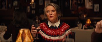 Movie still from “Bros” (2022), directed by Nicholas Stoller – An older woman holding a glass of red wine; Close Up shot, Over the shoulder angle