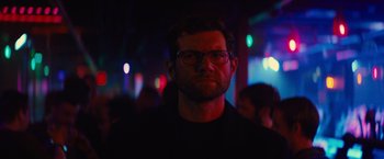 Movie still from “Bros” (2022), directed by Nicholas Stoller – A person wearing glasses in a dark room; Close Up shot, Low angle
