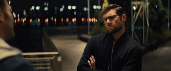 Movie still from “Bros” (2022), directed by Nicholas Stoller – A man with a beard wearing glasses and a black jacket; Close Up shot, Over the shoulder angle