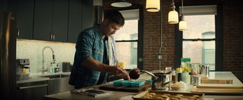 Movie still from “Bros” (2022), directed by Nicholas Stoller – A man in a plaid shirt is decorating a cake; Medium shot, Low angle