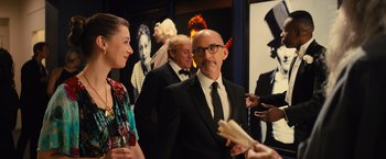 Movie still from “Bros” (2022), directed by Nicholas Stoller – A man in a suit and tie standing next to a woman in a dress; Medium shot, Over the shoulder angle