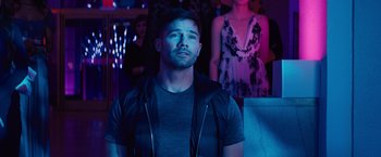 Movie still from “Bros” (2022), directed by Nicholas Stoller – A man in a black shirt and a woman in a black dress; Medium shot, Over the shoulder angle