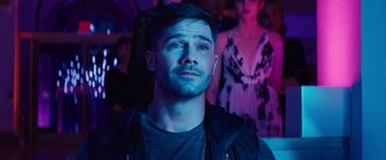 Movie still from “Bros” (2022), directed by Nicholas Stoller – A man with a beard is standing in front of a crowd; Close Up shot, Over the shoulder angle