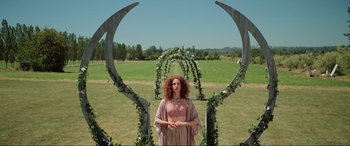 A woman standing in front of an archway in a field