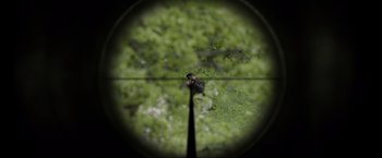 Movie still from “Burial” (2022), directed by Ben Parker – A view through a rifle scope of a tree; Extreme Close Up shot, High angle