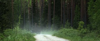 Movie still from “Burial” (2022), directed by Ben Parker – A man sitting on top of a truck in the middle of a forest; Extreme Wide shot, High angle
